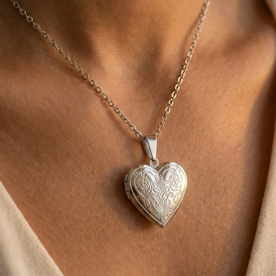 Heart-shaped silver locket on a chain worn by a person with a neutral background