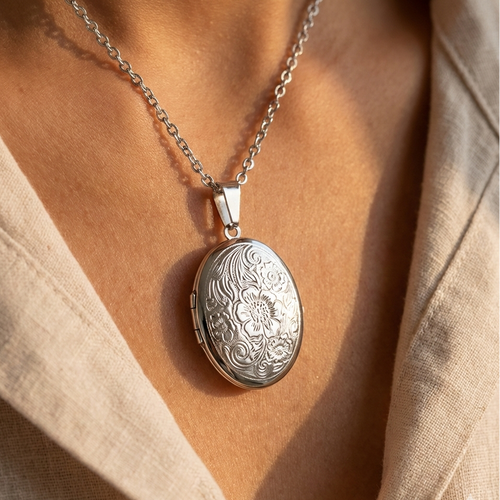 Silver locket necklace on a person wearing a beige top